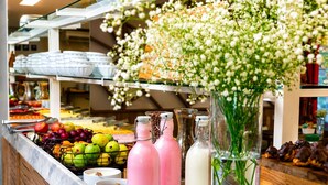 A buffet area with various fruits, beverages, and flowers.