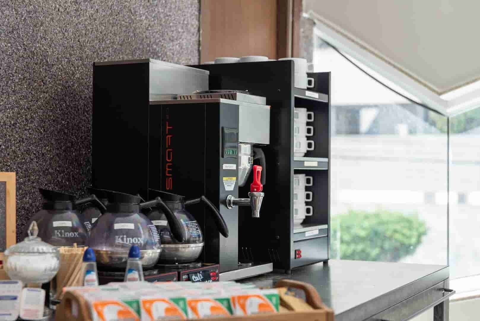 A coffee machine with multiple dispensers, a water bottle, and a coffee bag on a counter.