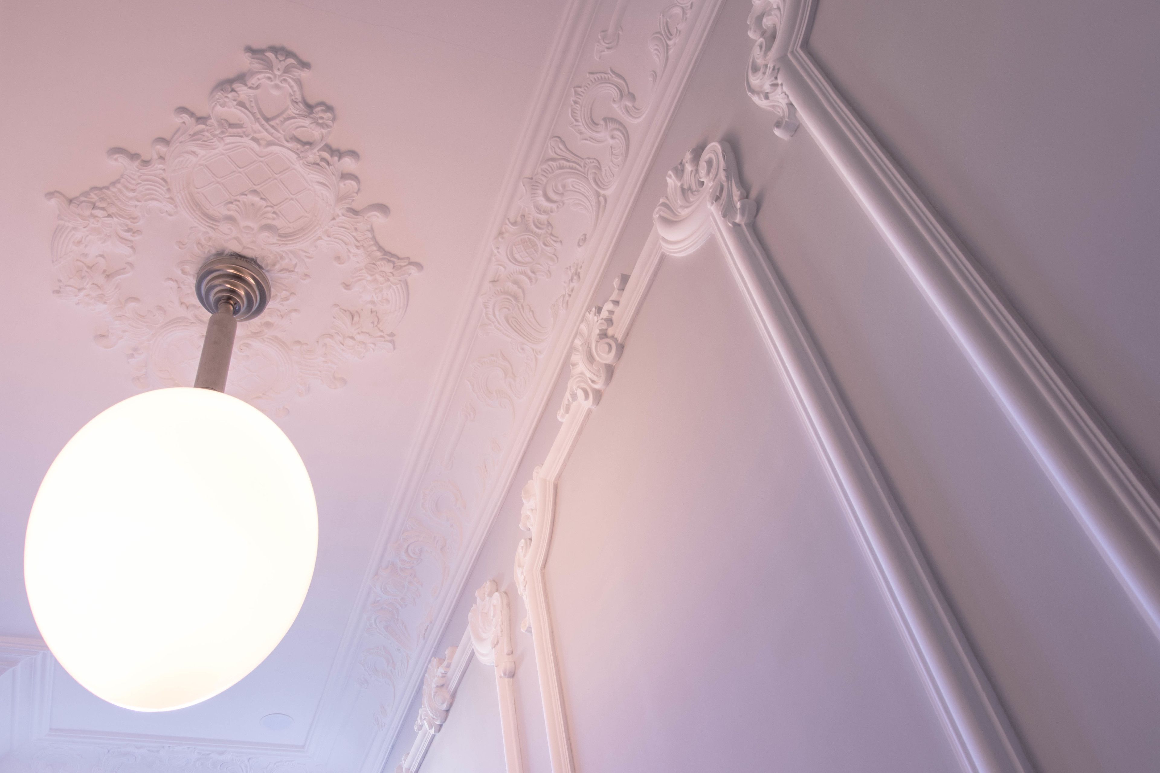 A ceiling with ornate plasterwork and a light fixture.