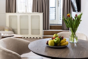 A dining table with a fruit bowl, a glass vase with tulips, and a white radiator in the background.