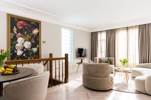 A spacious living room with a large painting, a dining area with fruit, and a modern sofa. - Canal Suites Amsterdam (Amsterdam)