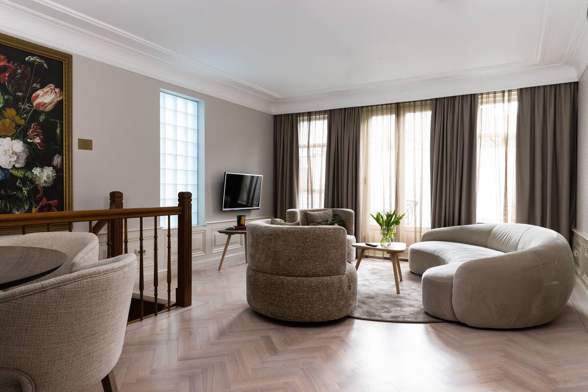A modern living room with a round coffee table, two sofas, a television, and a painting on the wall.