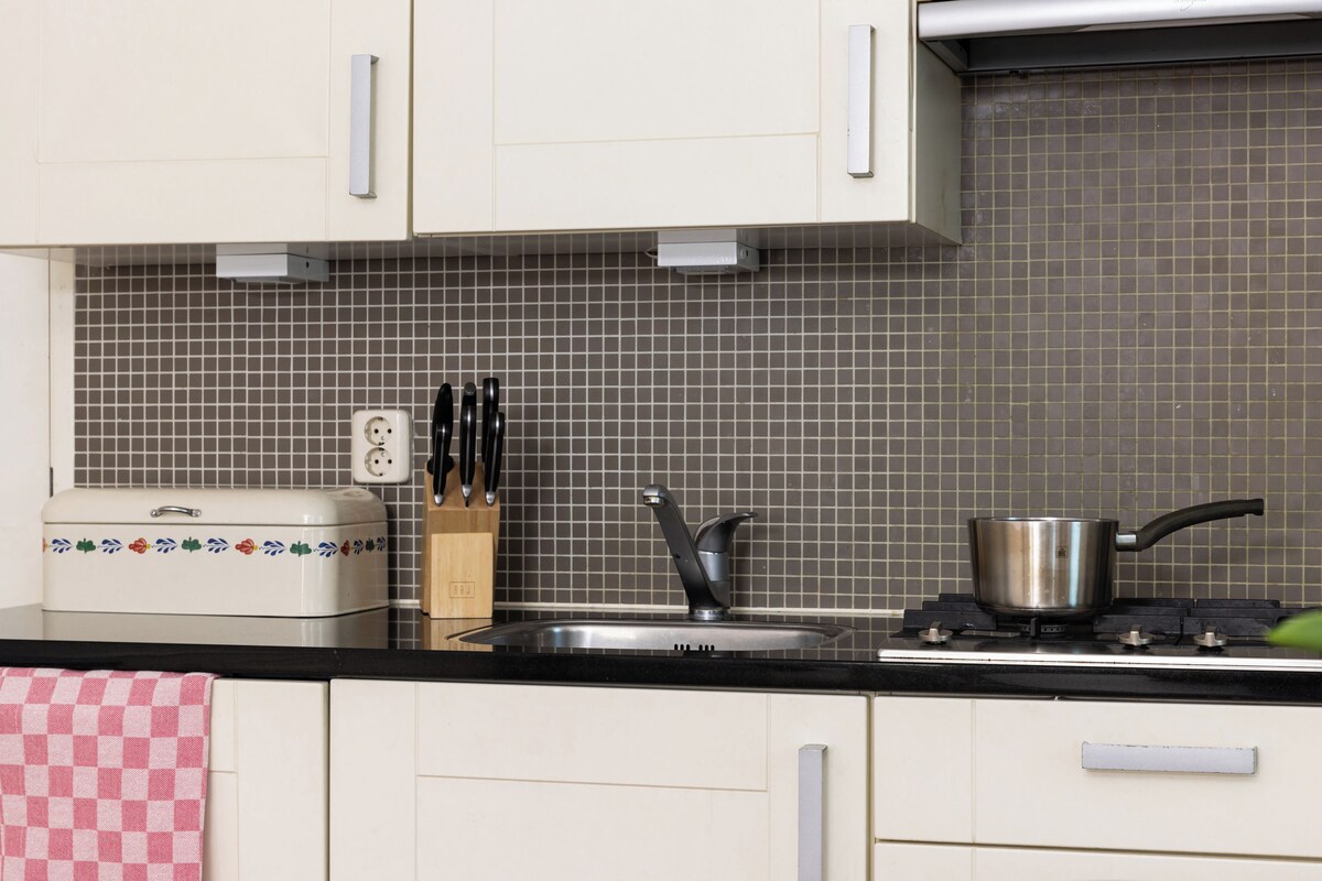 A kitchen with a toaster, a sink, a stove, and a knife block.