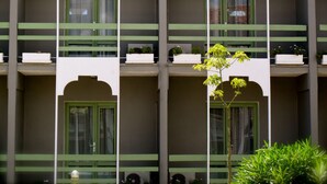 Un immeuble doté de nombreux balcons, chacun orné d’une rambarde verte et de plantes en pot.