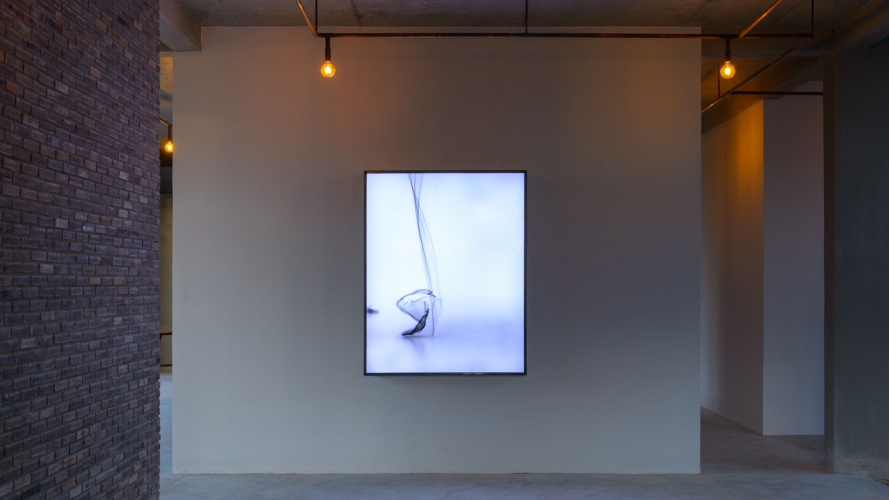 Un espacio de galería minimalista con una única obra expuesta.