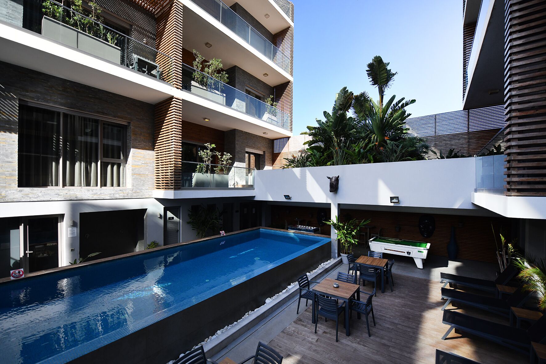 A modern building with a rooftop pool, outdoor seating, and multiple balconies.