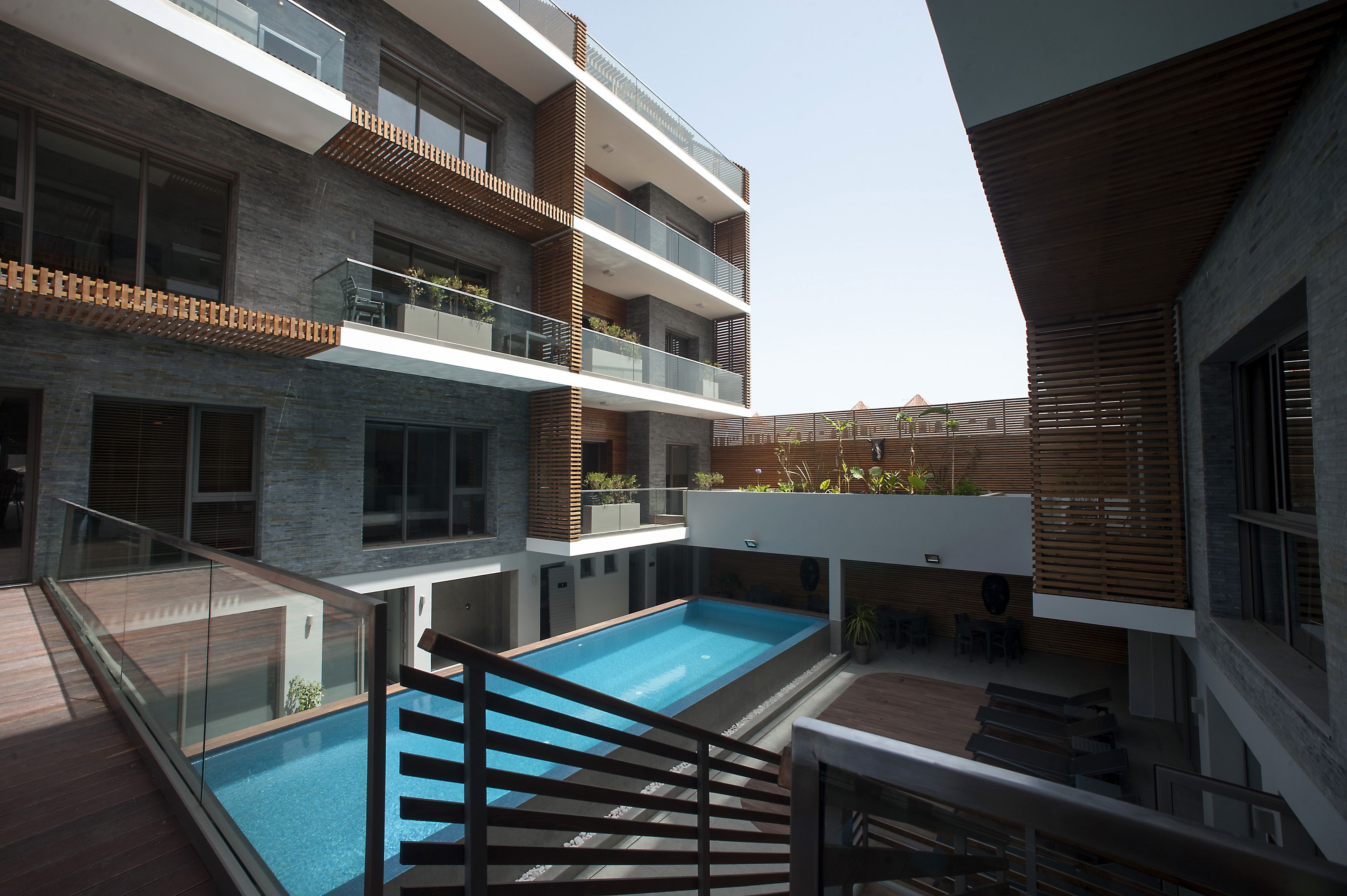 A modern building with a rooftop pool, multiple balconies, and a mix of brick and wood materials.