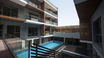 A modern building with a rooftop pool, multiple balconies, and a mix of brick and wood materials.