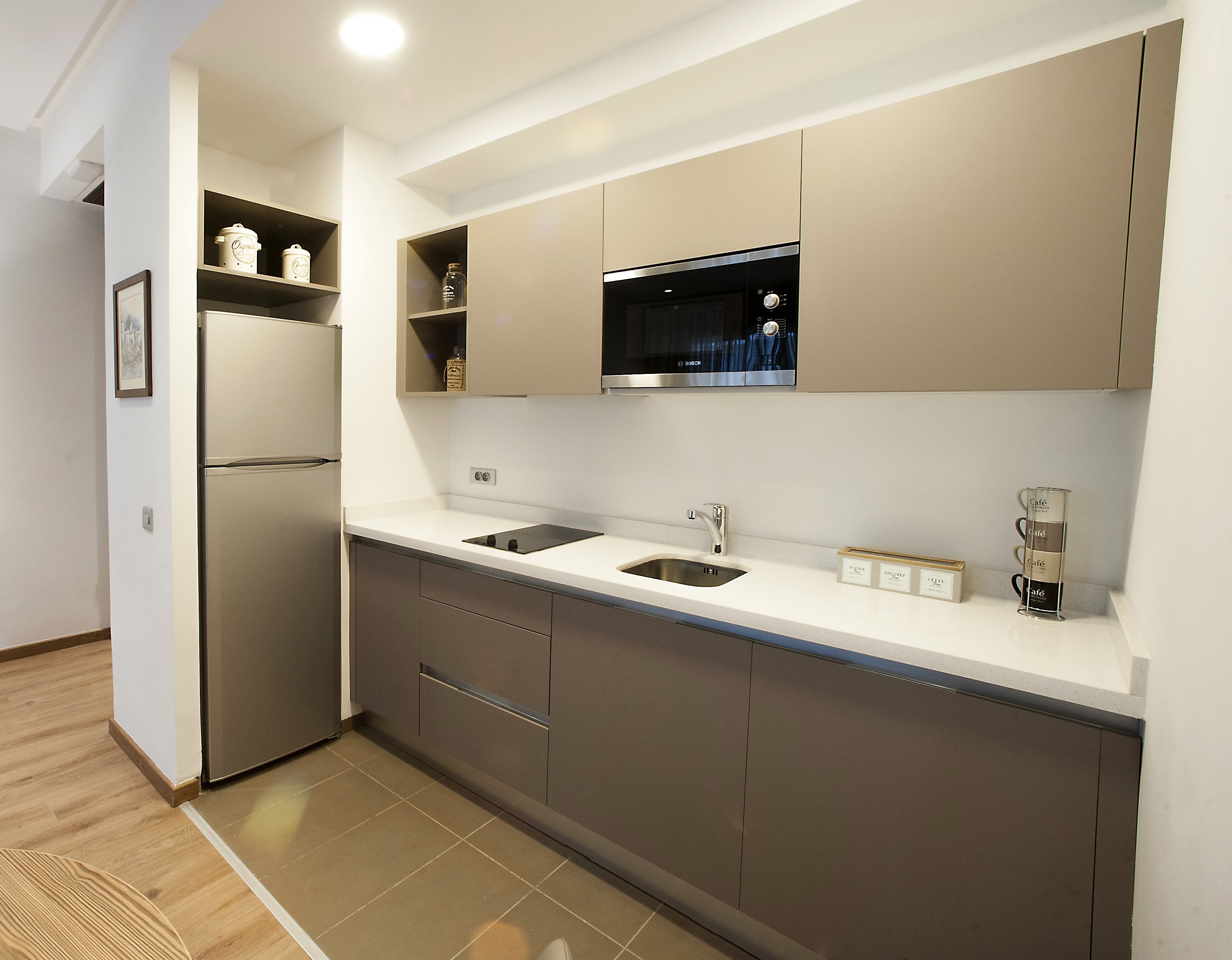 Una cocina moderna con microondas integrado, dos fregaderos y un refrigerador.