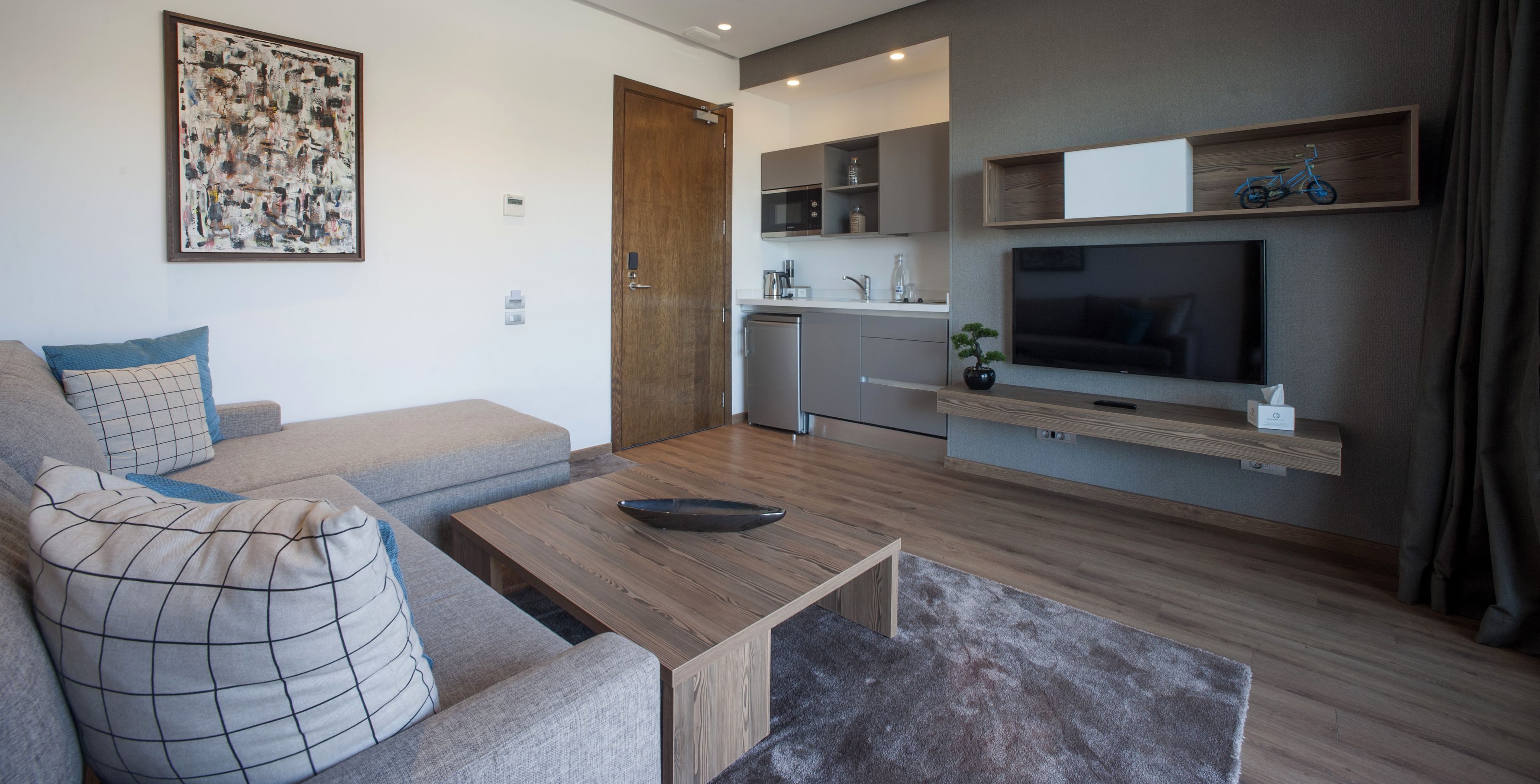 A modern living room with a sofa, coffee table, and a flat-screen TV mounted on the wall.
