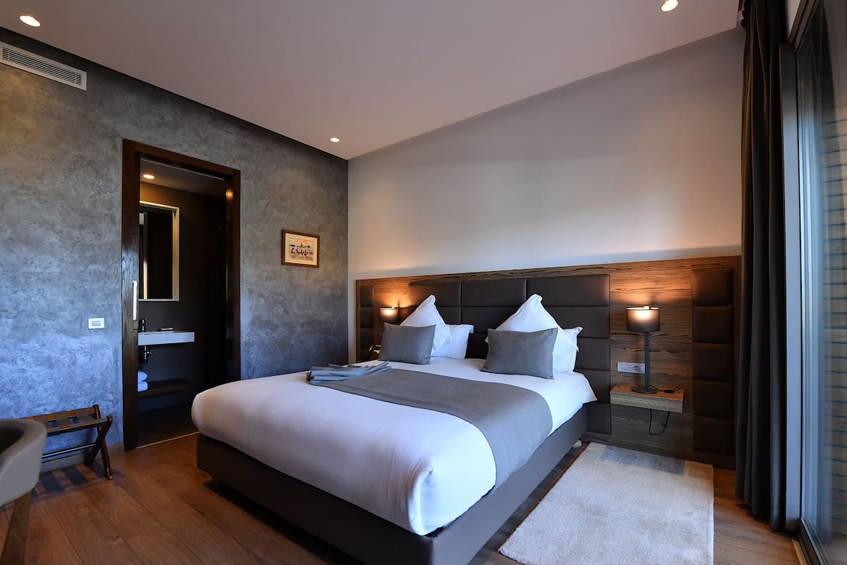 Une chambre à coucher moderne avec un grand lit, une table de chevet avec une lampe et une tête de lit en bois.