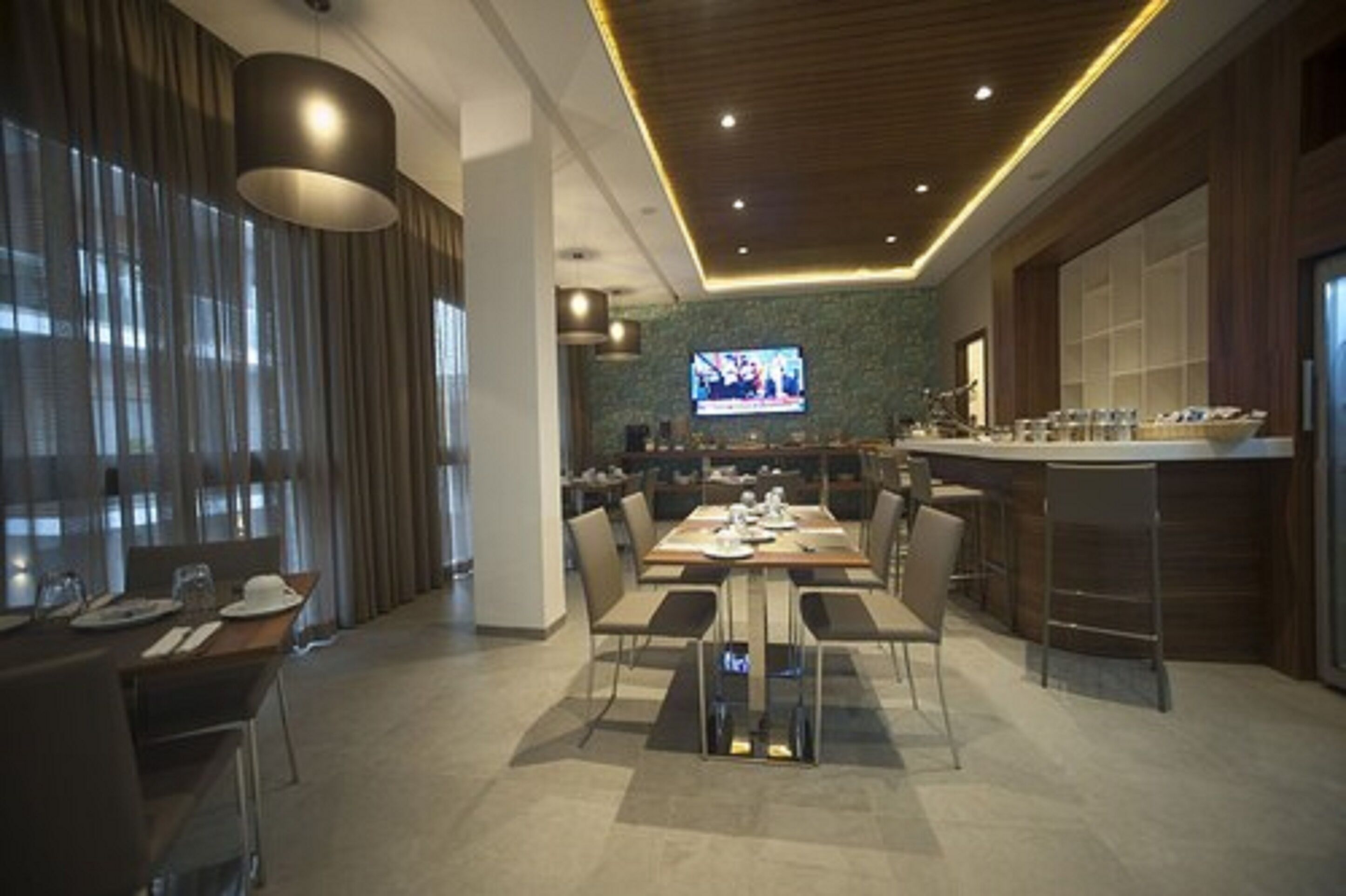 A modern dining area with a long table, chairs, and a bar counter.