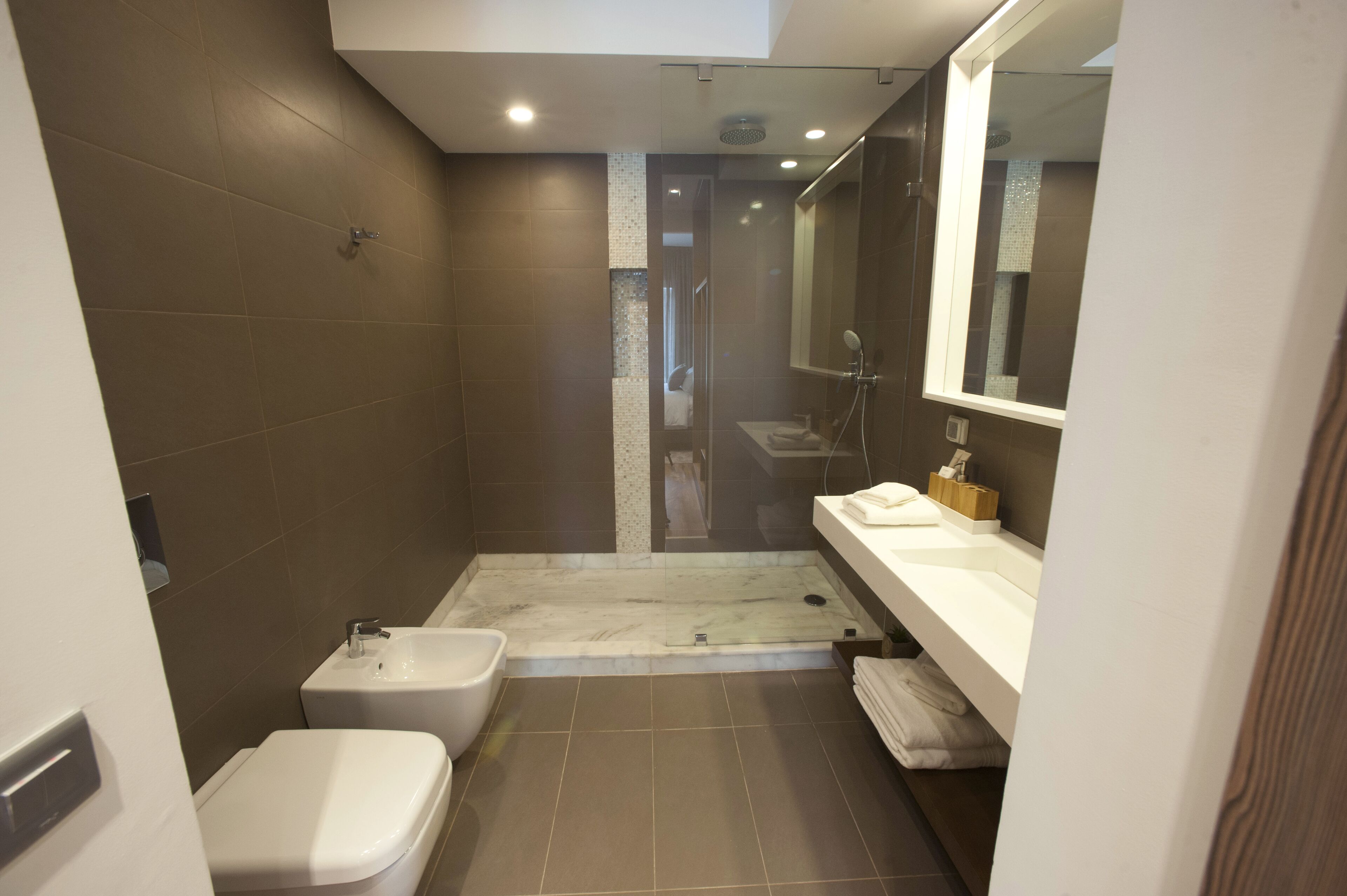 A modern bathroom with a shower, toilet, and sink.