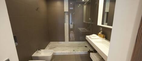 A modern bathroom with a shower, toilet, and sink.