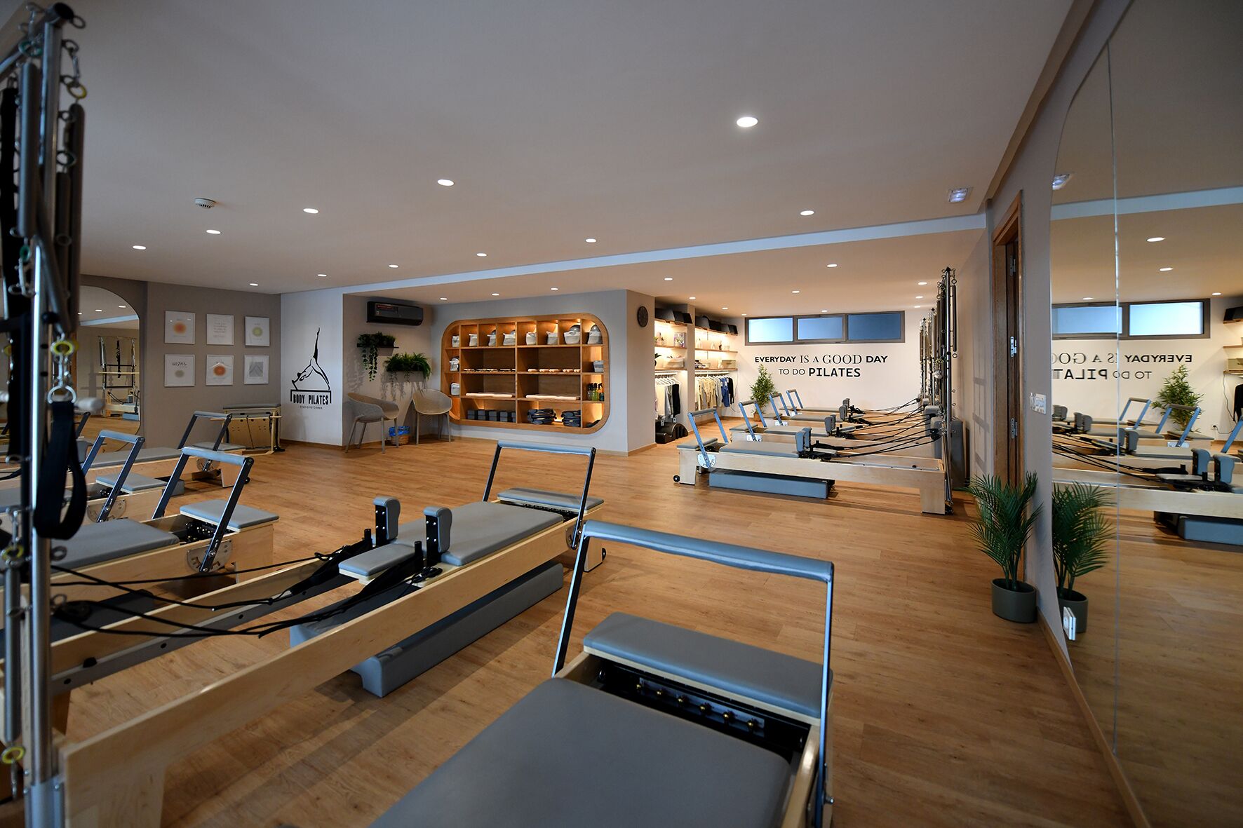 Een Pilates studio met apparatuur, houten vloeren en een muur met inspirerende citaten.
