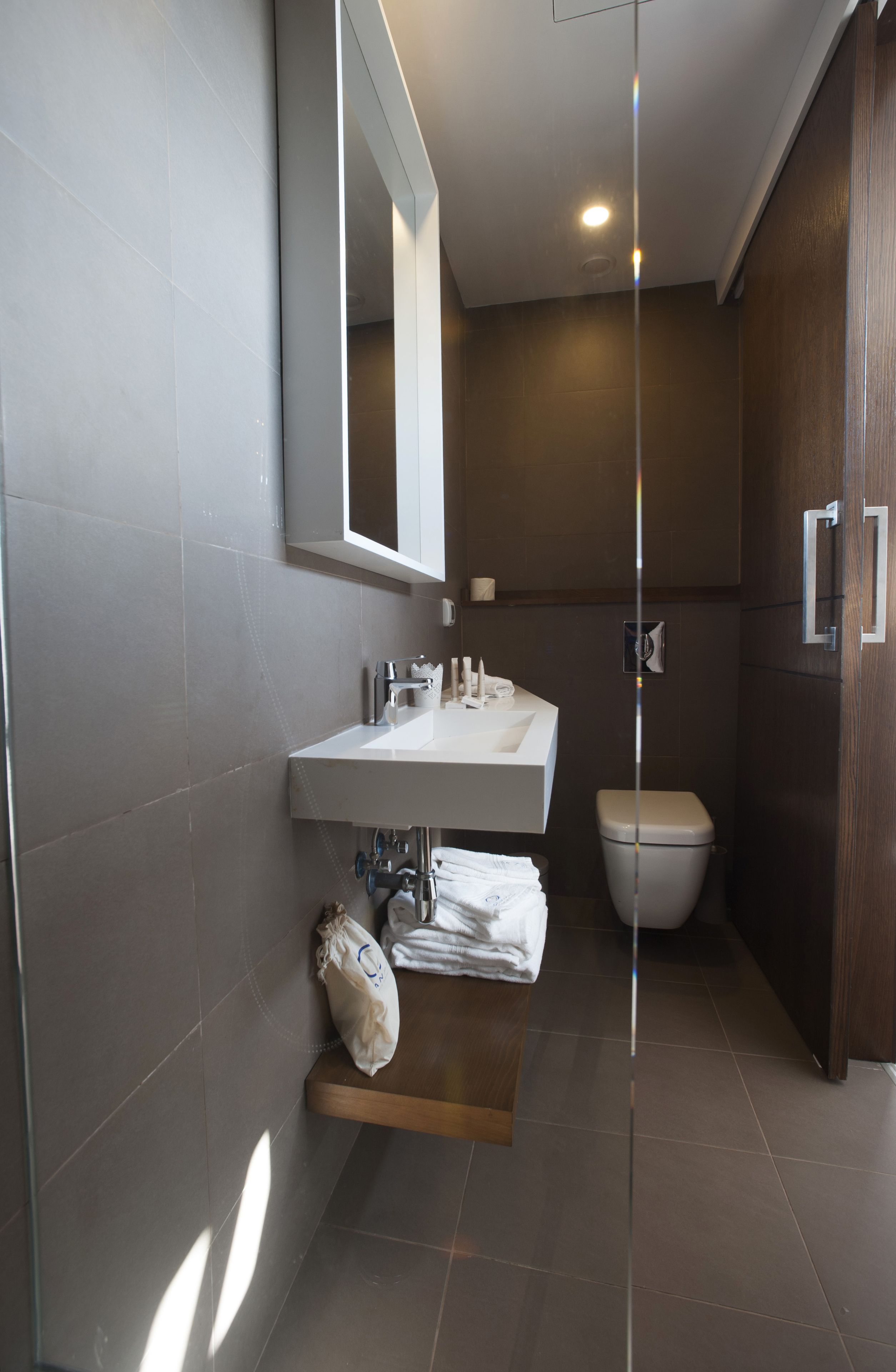 A modern bathroom with a white sink, mirror, and toilet.