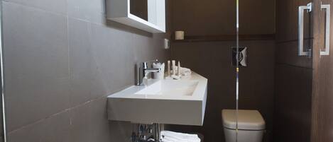 A modern bathroom with a white sink, mirror, and toilet.