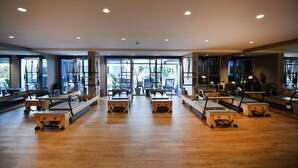 Une pièce spacieuse dotée d’un plancher en bois, de grandes fenêtres et d’appareils de Pilates.