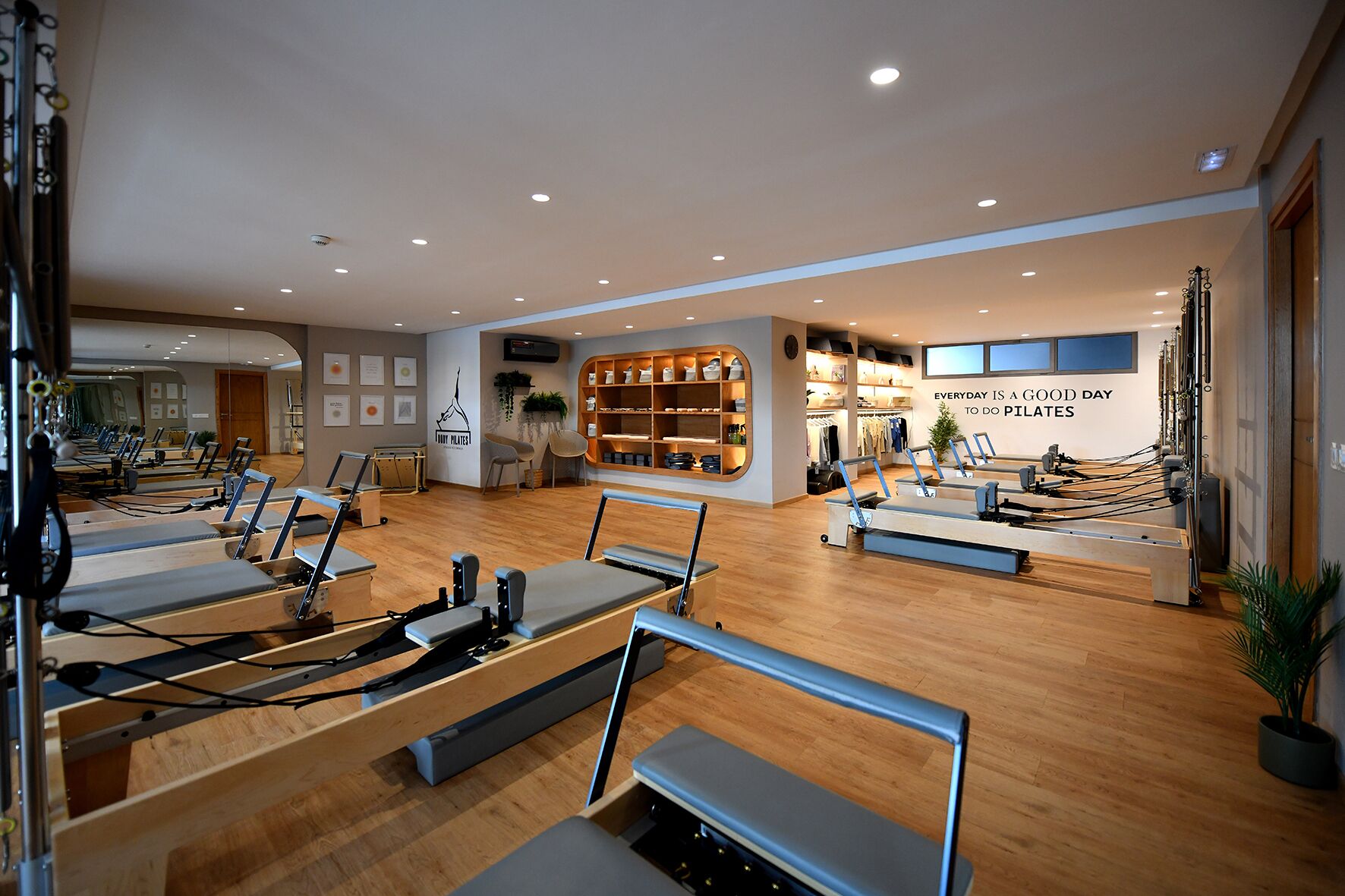 Un studio de Pilates équipé de plusieurs appareils, doté de planchers en bois et orné d’une citation inspirante sur le mur.