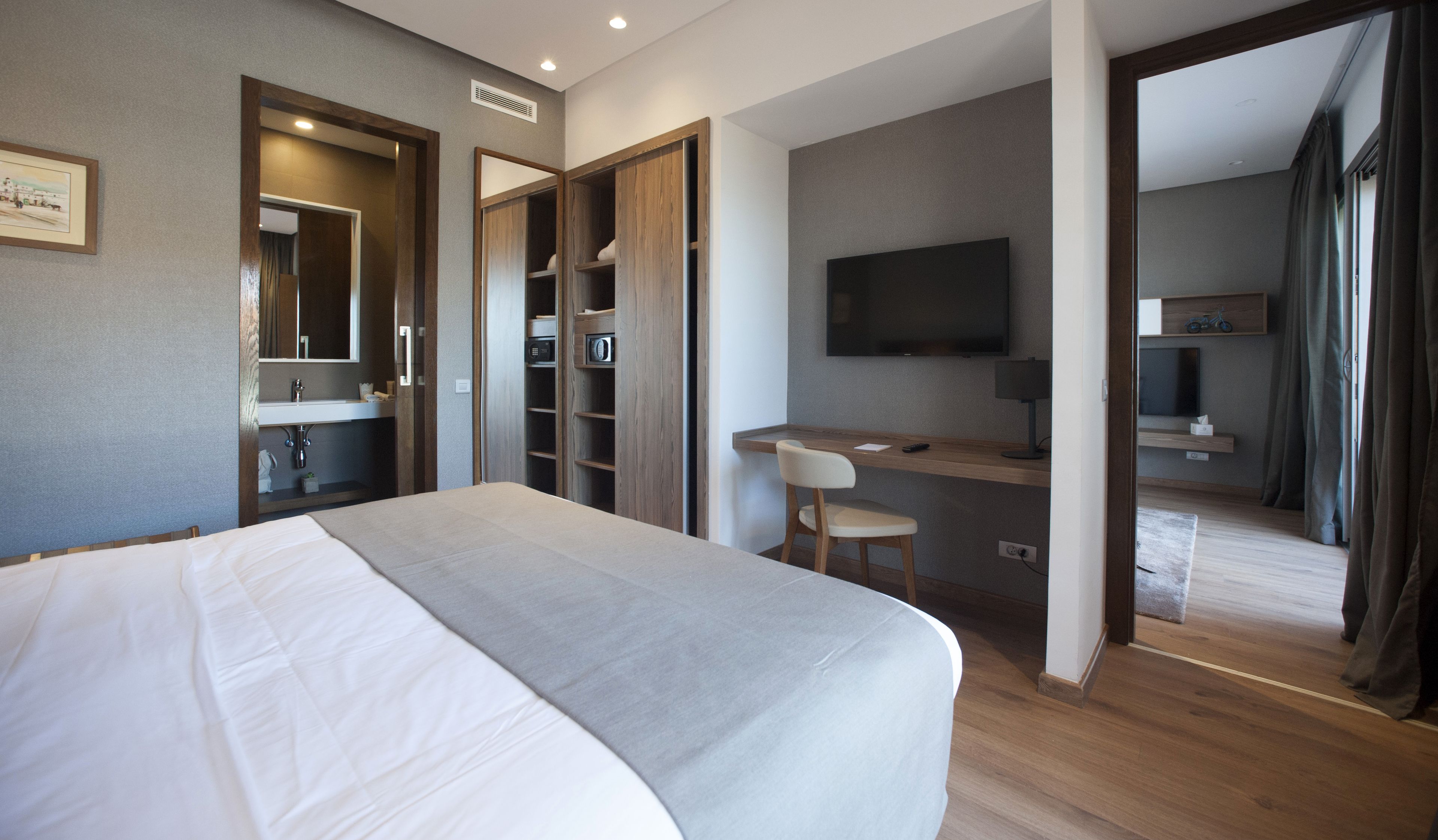 Une chambre d’hôtel moderne dotée d’un grand lit, d’un bureau, d’une télévision et d’un dressing.