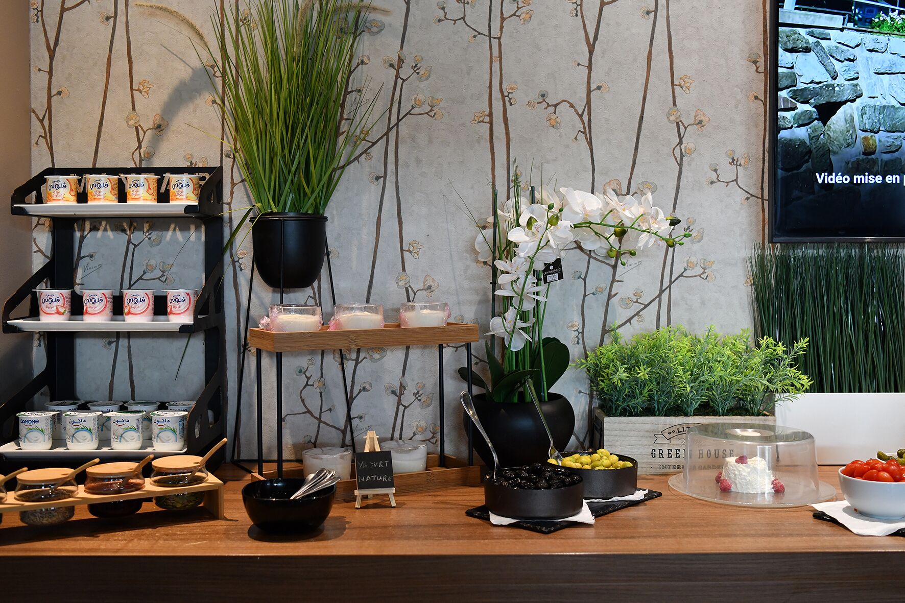 A reception area with a wooden counter, potted plants, and various food items.