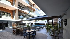 Un espace extérieur moderne, comprenant un patio, une piscine, une terrasse en bois et des sièges.