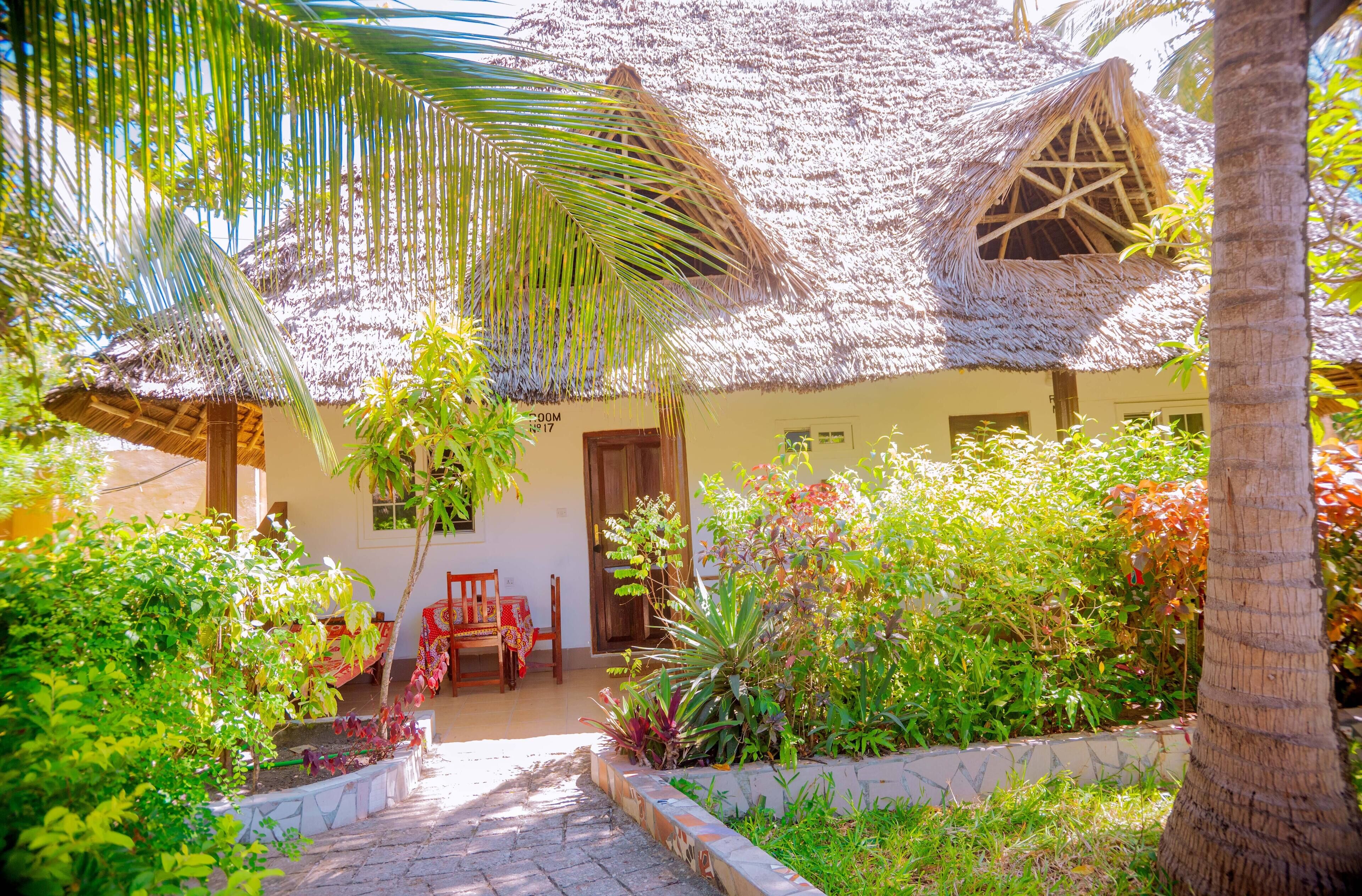 Uma casa com telhado de palha e um jardim na frente.