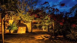 Un sendero pavimentado que conduce a una estructura de madera con un letrero que dice "LA COZINHA".