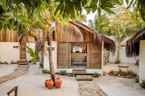 Een tropisch resort met houten hutten, een rieten dak en een zandpad.