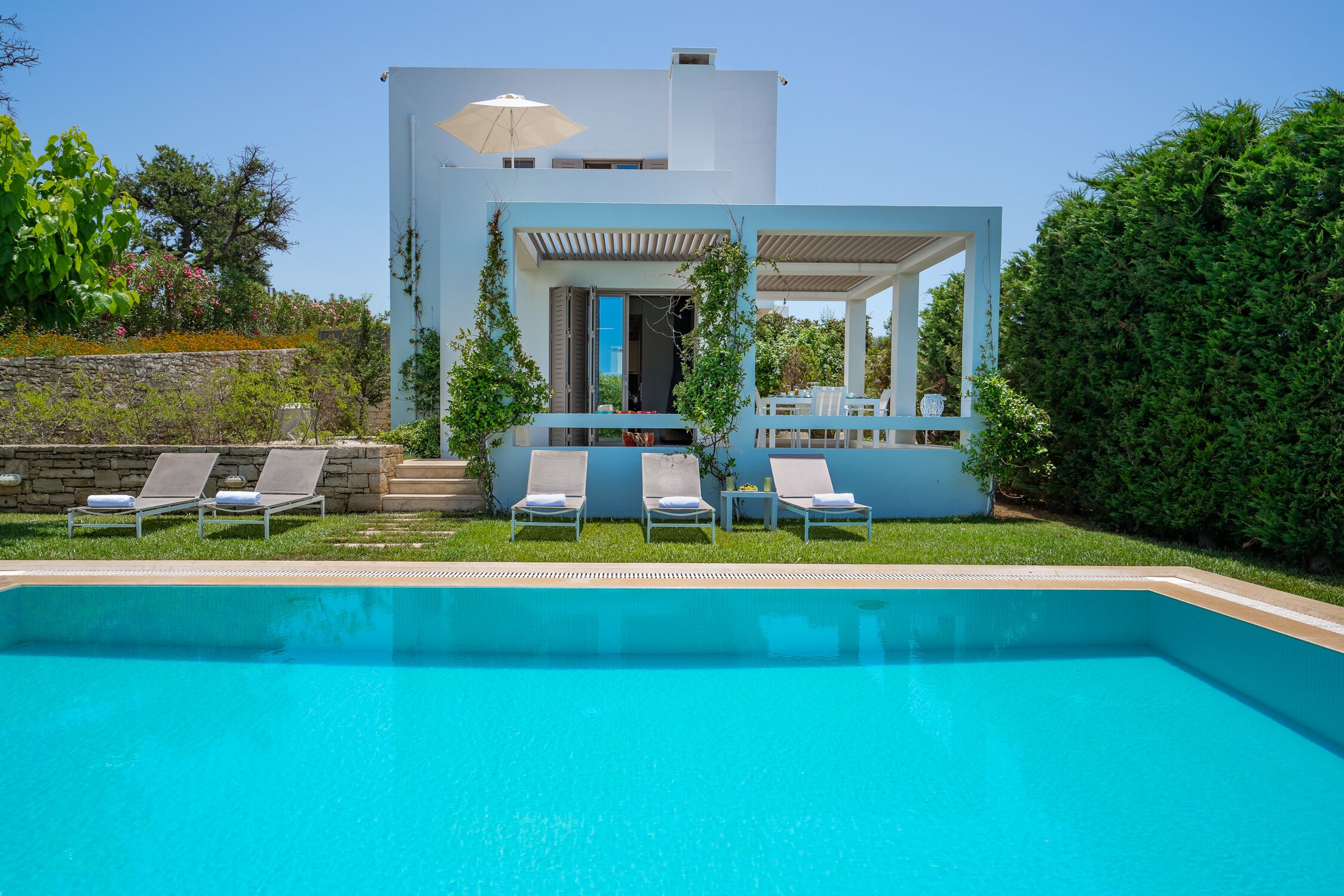 A modern house with a swimming pool, outdoor seating, and a covered patio area.