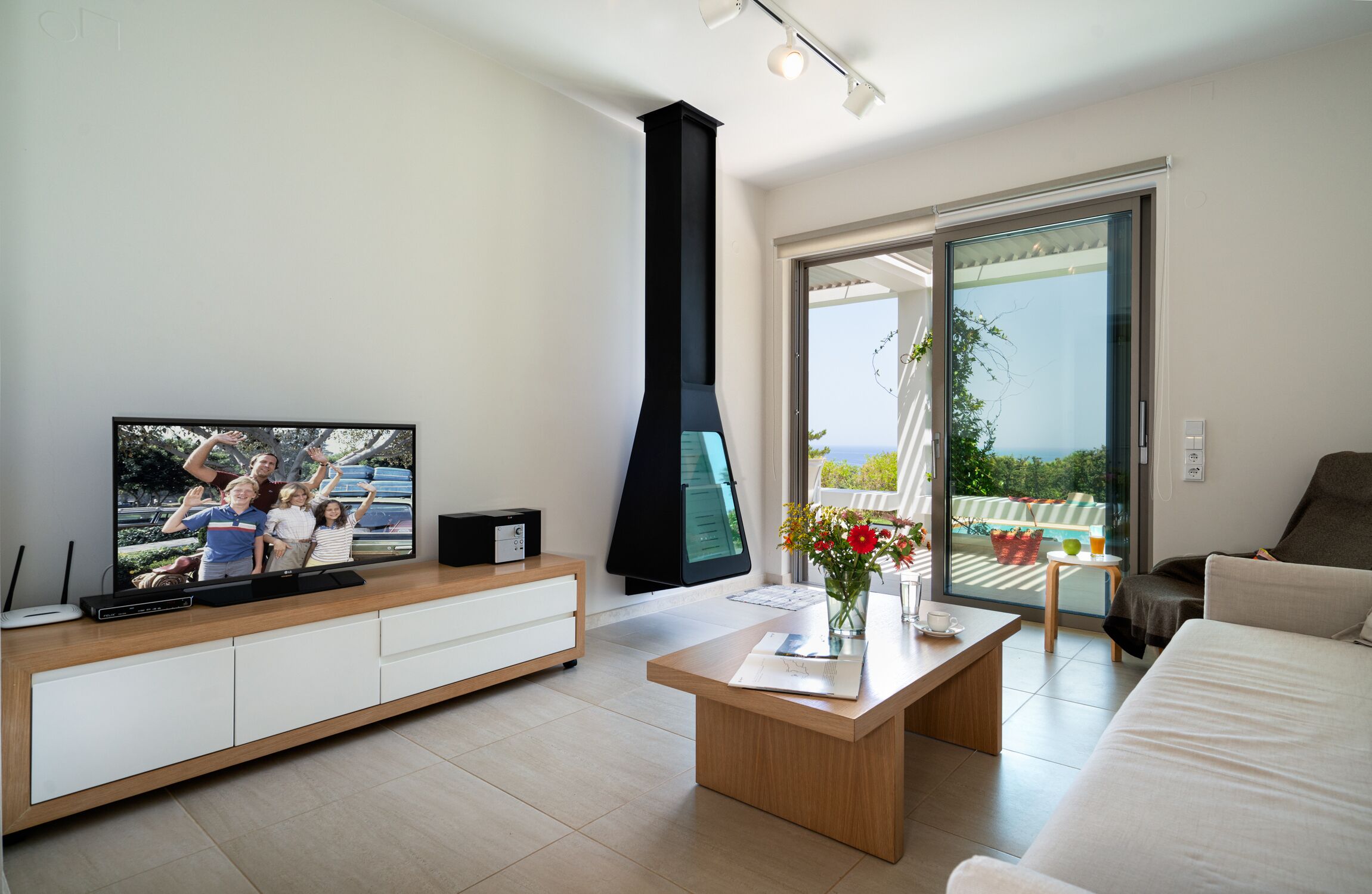 A modern living room with a TV, a fireplace, a balcony with a view, and a dining area.