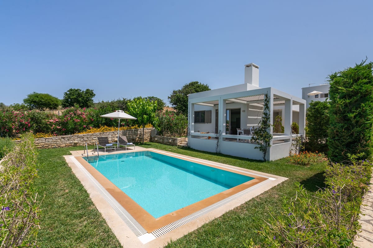 A modern house with a swimming pool, a covered patio, and a stone wall.