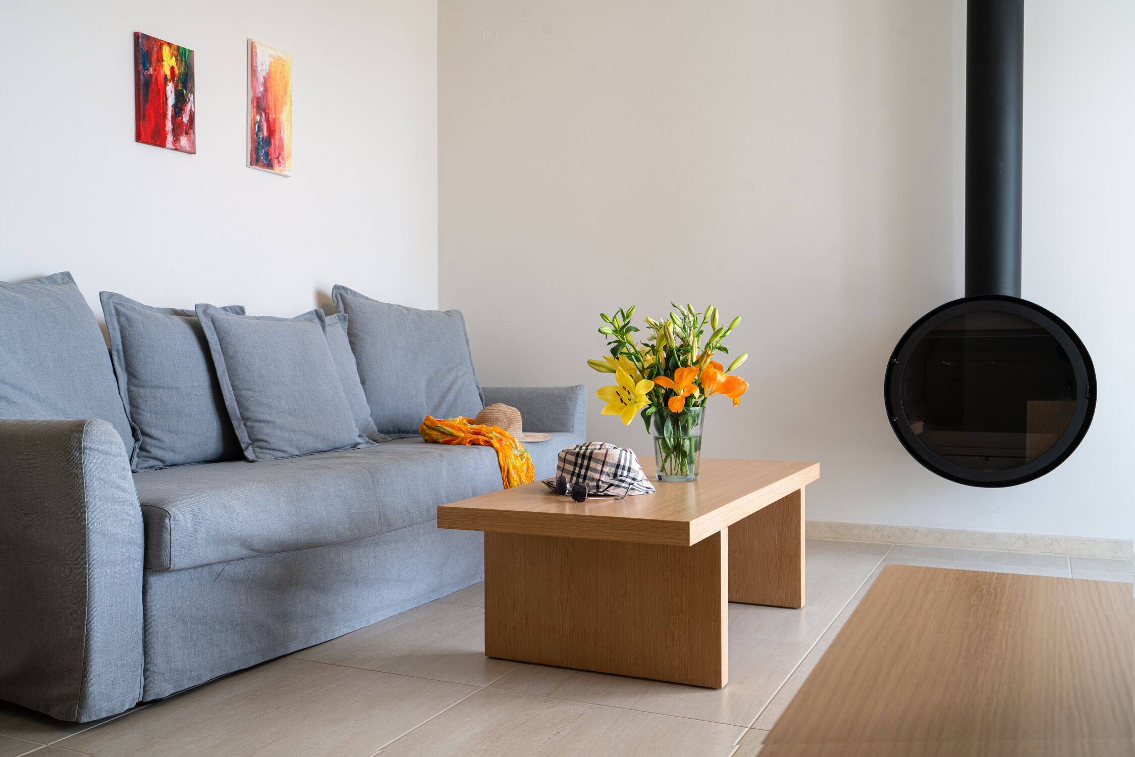 A modern living room with a grey sofa, a wooden coffee table, and a vase of flowers.