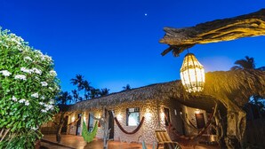 A thatched-roof building with a hammock and a hanging light fixture. - Pousada Titas (Cajueiro da Praia)