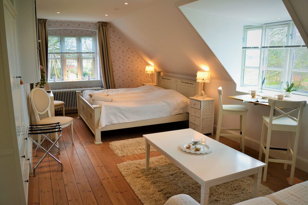 A bedroom with a bed, a desk, a chair, and a radiator.