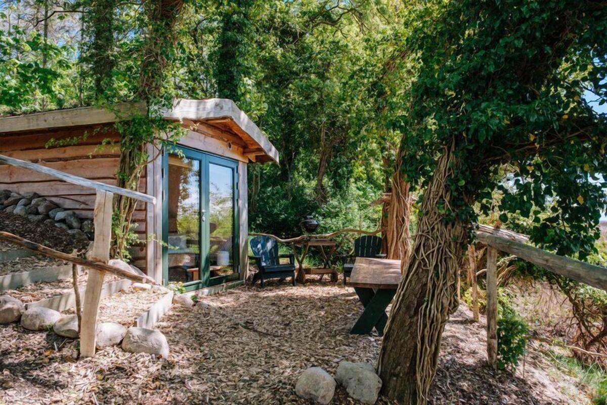 A rustic cabin with a glass door, surrounded by trees and a wooden deck.
