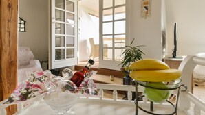 A room with a white chair, a table with a glass bowl, a bottle, and a potted plant. - Jungshoved Præstegård (Praesto)