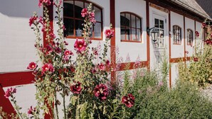 A white building with red trim, multiple windows, and a thatched roof. - Jungshoved Præstegård (Praesto)