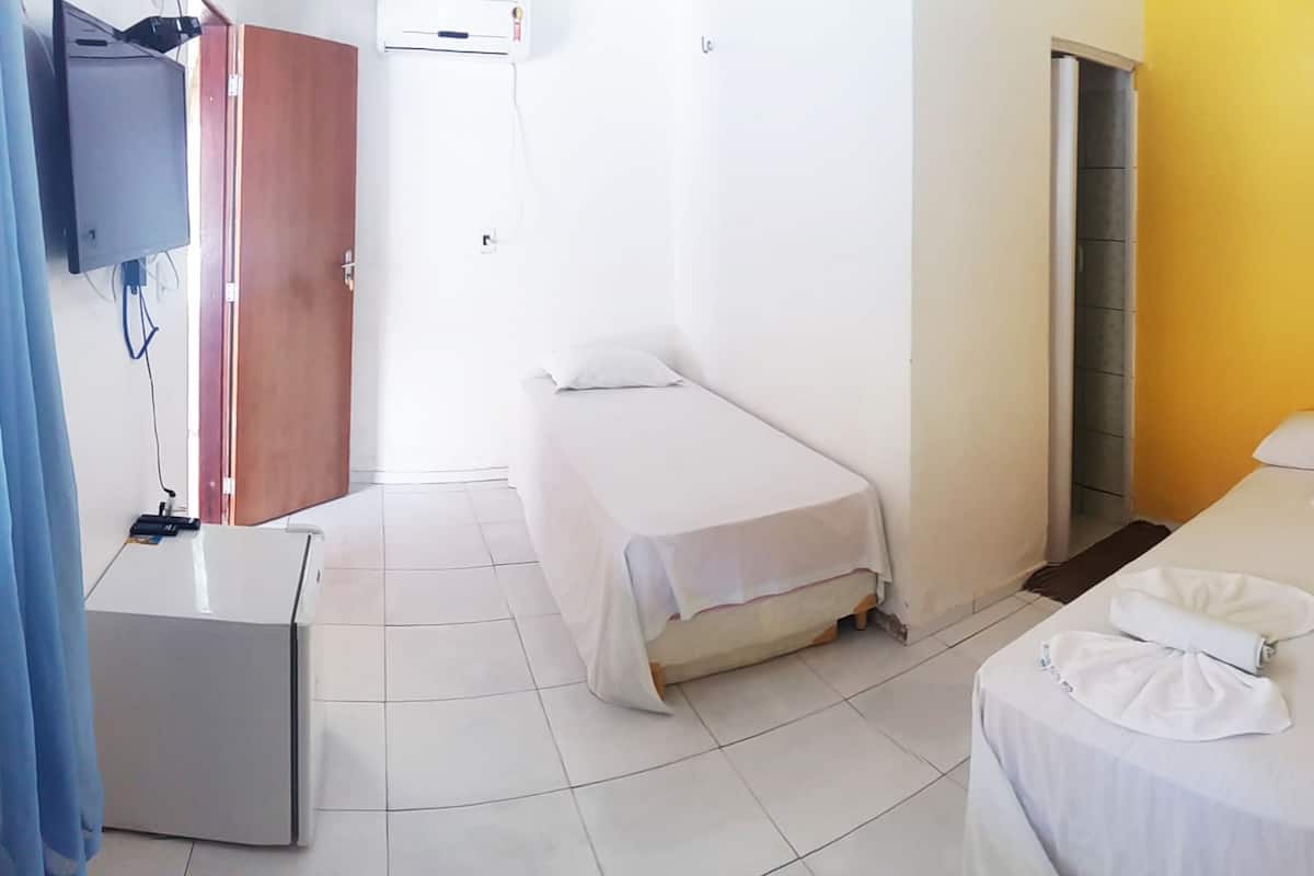 A hotel room with two single beds, a small desk, and a television.