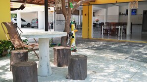An outdoor seating area with a round table and chairs, surrounded by wooden stumps. - Pousada Beira Rio Parnaiba (Parnaíba)