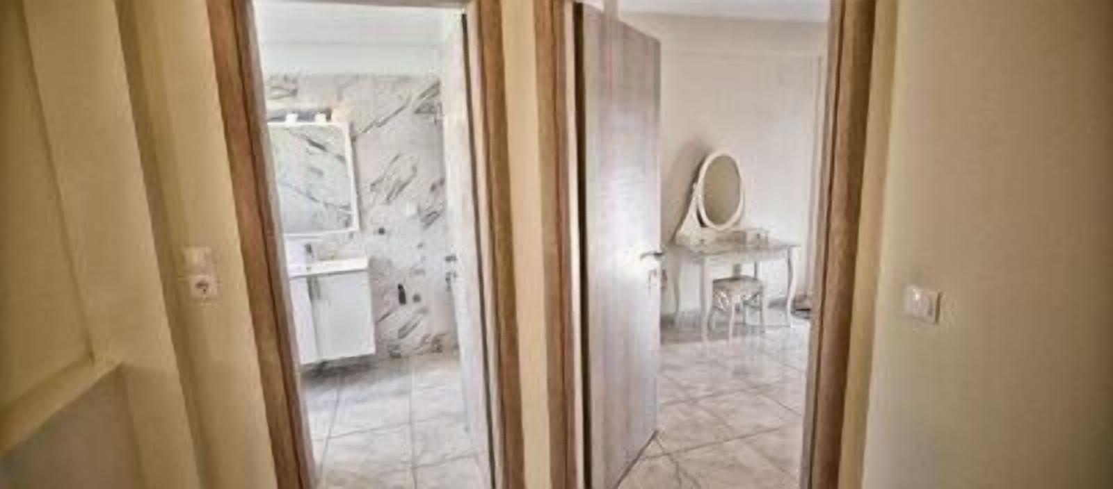A bathroom with a marble floor, a sink, and a mirror on a stand.