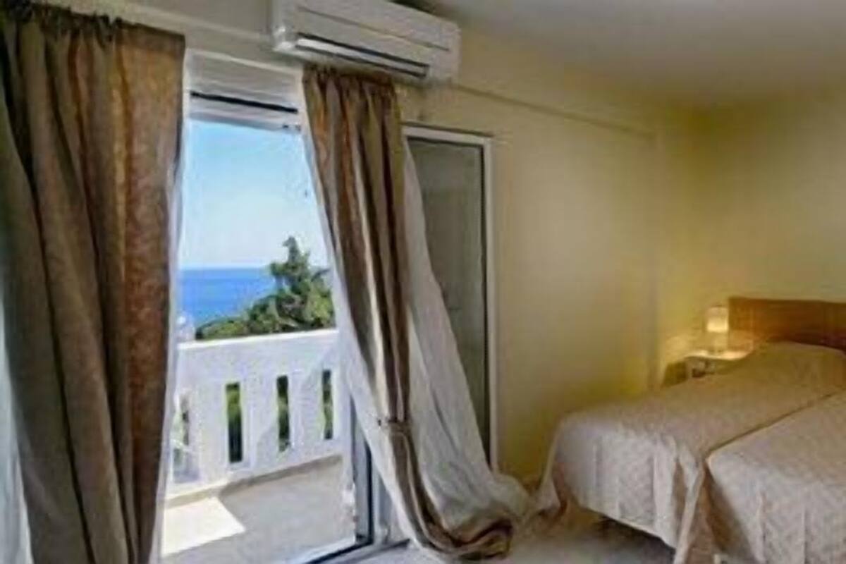 A hotel room with a bed, bedside tables, and a view of the sea.