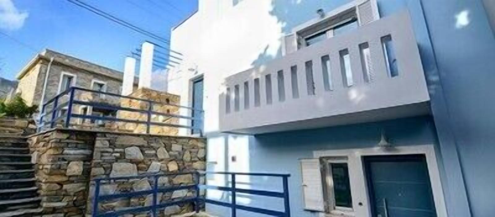 A modern building with a stone facade and a blue balcony.
