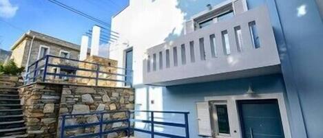 A modern building with a stone facade and a blue balcony.