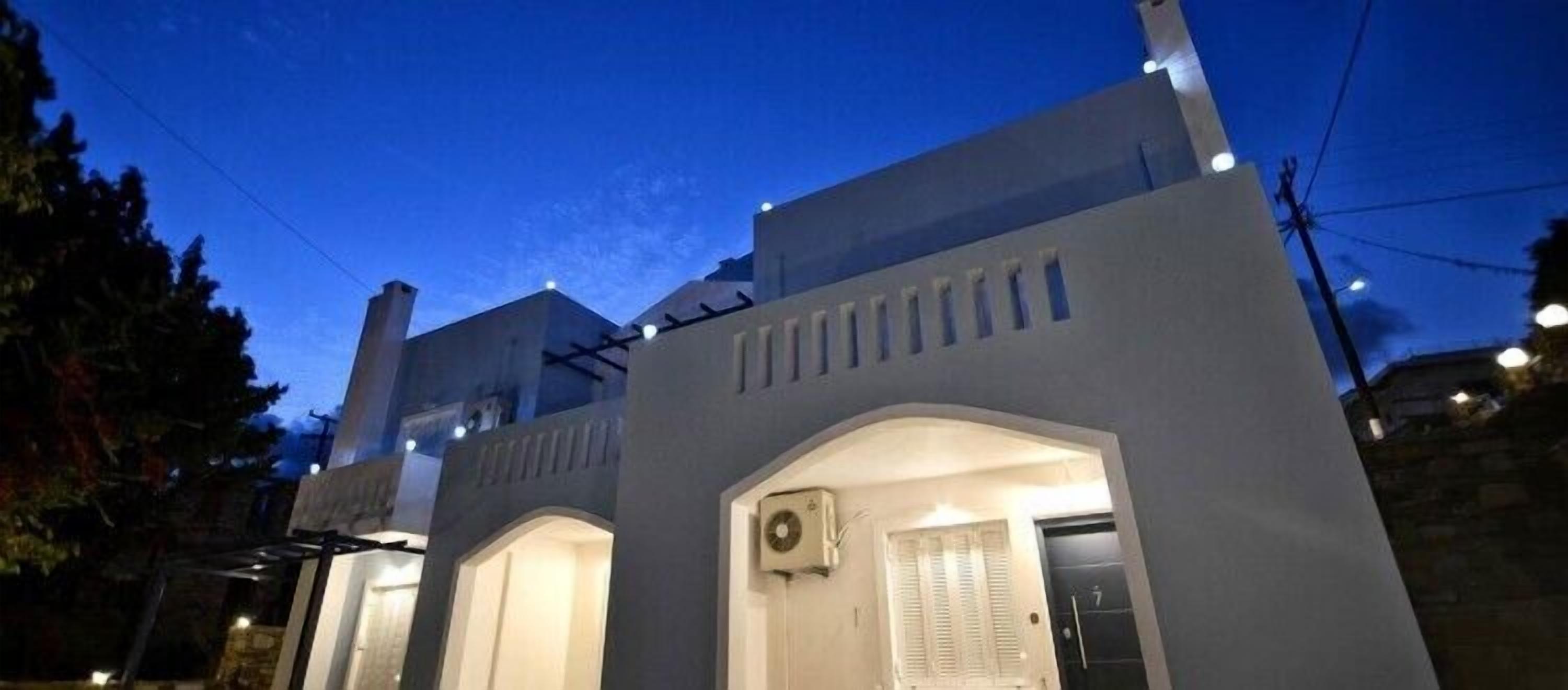 A modern building with a flat roof, a central arched entrance, and a small balcony.