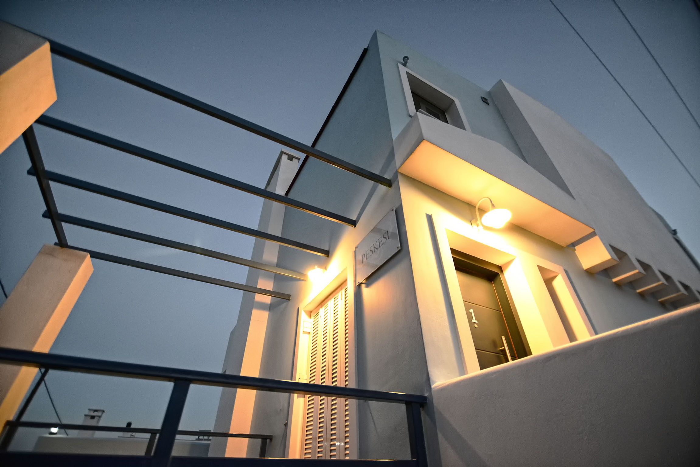 Un edificio moderno con balcón y entrada iluminada.