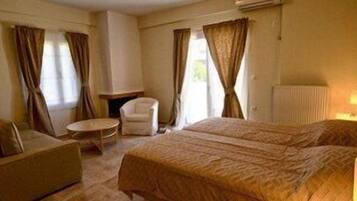 A hotel room with two beds, a chair, a small table, and curtains.