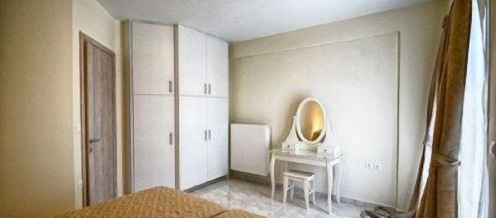 Ein Schlafzimmer mit einem Bett, einem Kleiderschrank, einem Schminktisch und einer Tür.