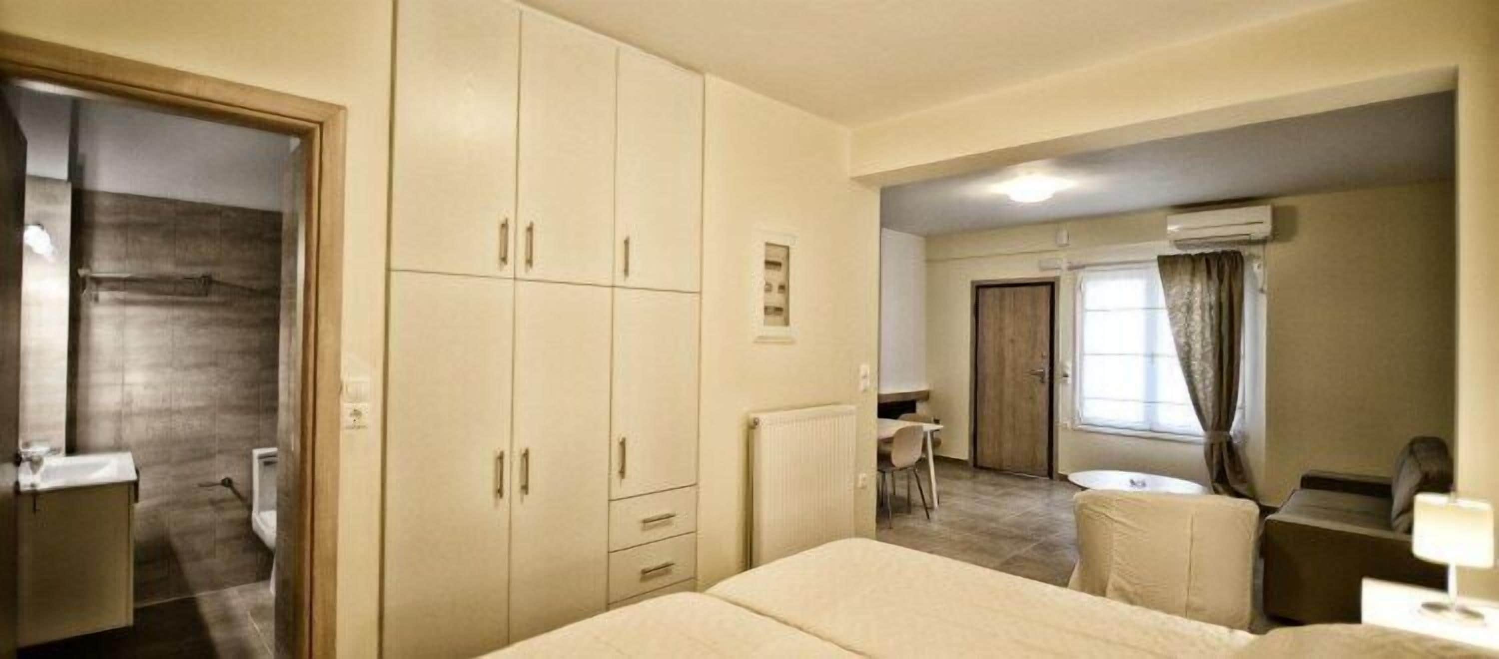 A hotel room with a large bed, a desk, a chair, and a wardrobe.