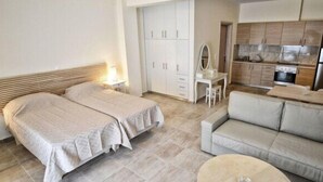 Un dormitorio con dos camas, un sofá, un escritorio y una kitchenette.